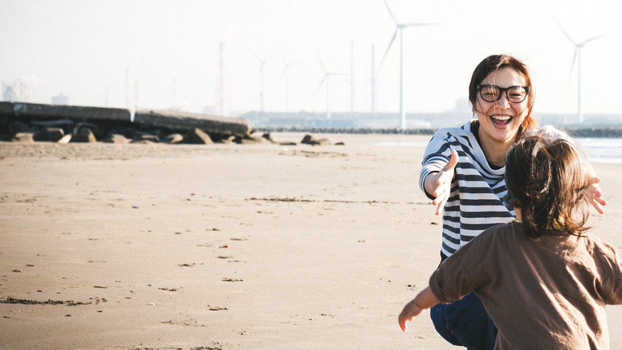 Dziecko biegnące do matki na plaży z wiatrakami