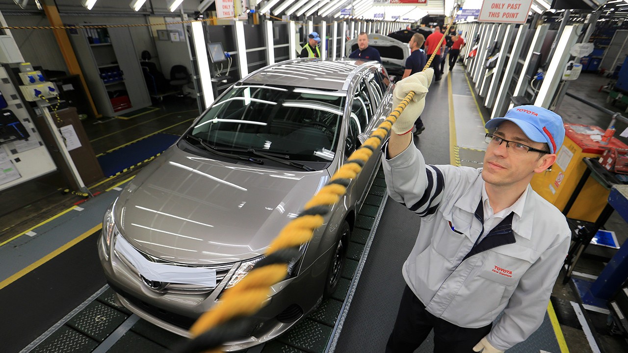Pracownicy w fabryce Toyota trzymający linkę andon